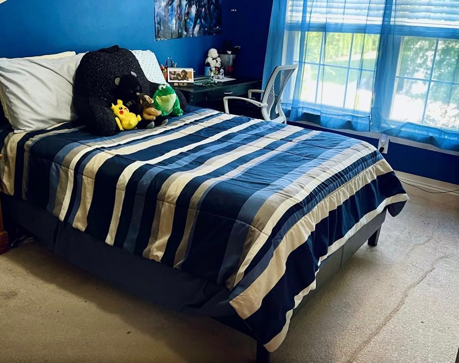 The same bedroom with the striped bedding neatly made and the carpet clear after cleaning