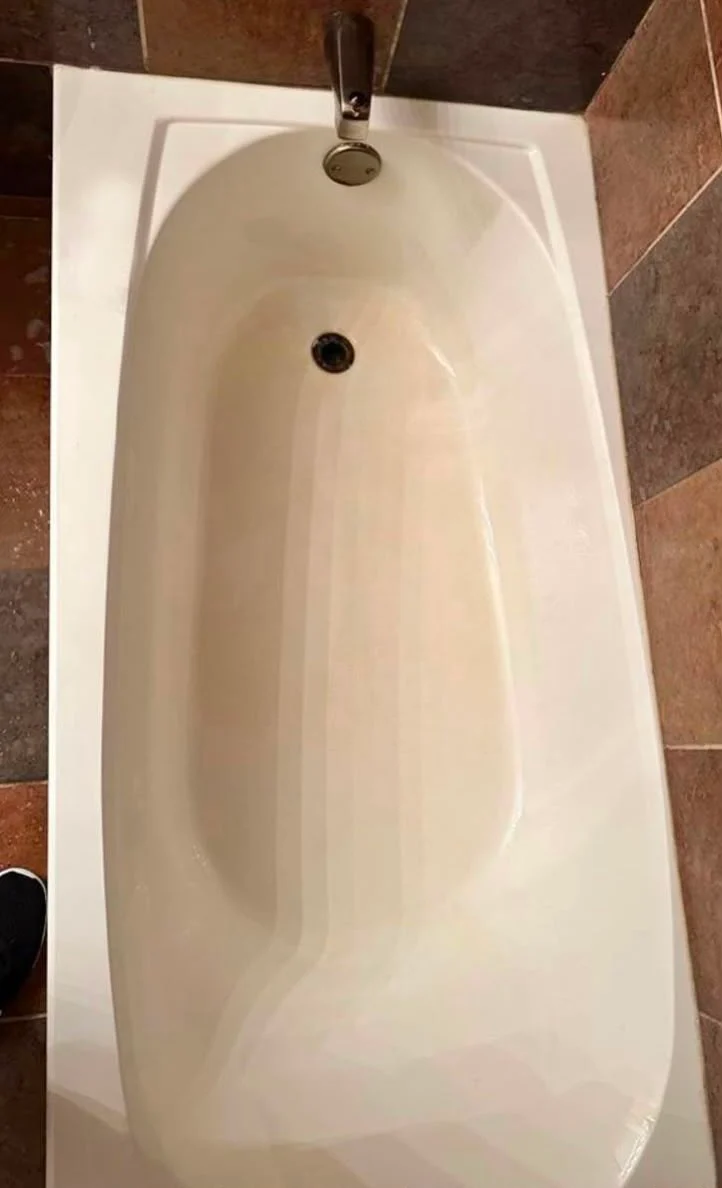 The same bathtub restored to a clean white finish after deep cleaning